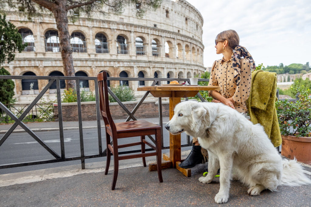 Woman with her dog at outdoor cafe in front of coliseum in Rome, Italy